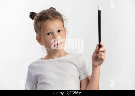 Fille magicienne - baguette magique dans les mains d'enfant - jeune magicien exécutant avec une baguette magique - sur fond blanc Banque D'Images