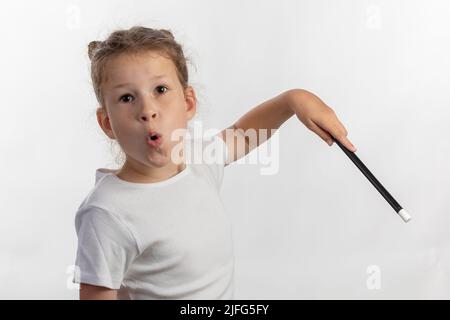 Fille magicienne - baguette magique dans les mains d'enfant - jeune magicien exécutant avec une baguette magique - sur fond blanc Banque D'Images