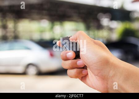 La main de l'homme appuie sur la commande à distance des systèmes d'alarme de voiture Banque D'Images