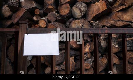 Maquette de panneau sur clôture avec stockage de bois de chauffage empilé, fond naturel. Maquette de la mise en page des stocks de bois de grumes prêt pour votre aperçu de conception. Billboa Banque D'Images