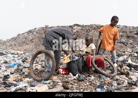 Trois garçons de rue sans abri dans une décharge avec leur pillage quotidien des ordures à recycler et à vendre; état des enfants de taudis en Afrique Banque D'Images