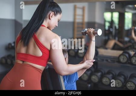 Entraîneur personnel aide à l'entraînement du client par des haltères au miroir Banque D'Images