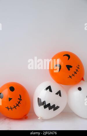 Les jacks peints font face aux ballons. Préparation des boules orange et blanches pour halloween. Activités à la maison pour Halloween. Jouets faits main artisanat pour enfants Banque D'Images