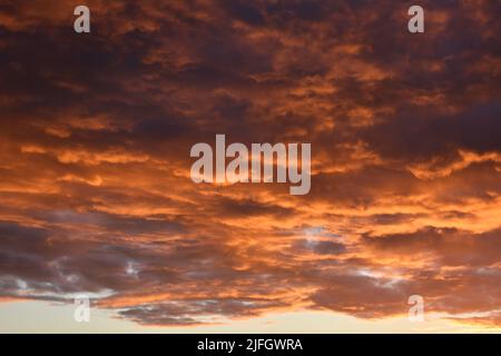 Ciel noir et orange spectaculaire tandis que les nuages Nimbostratus se rassemblent au coucher du soleil juste avant une tempête de pluie d'été Banque D'Images