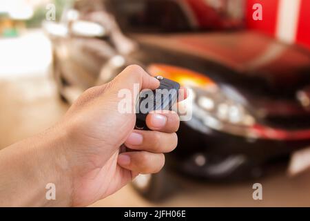 La main de l'homme appuie sur la commande à distance des systèmes d'alarme de voiture Banque D'Images