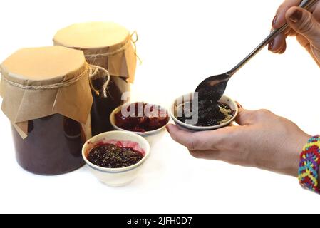 Une main servant de la confiture de mûres maison dans de petits bols en pots Banque D'Images