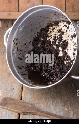 huile à base de plantes ayurvédiques maison dans une casserole, henné, aloe vera et thé en poudre mélangé et bouilli avec de l'huile de coco, placé sur une surface en bois Banque D'Images