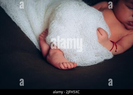 Jambes d'un nouveau-né. Pieds de bébé recouverts d'une couverture blanche. Le pied minuscule d'un nouveau-né en foyer doux sélectif. Photo de haute qualité Banque D'Images