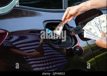 main de femme qui met l'argent dans le réservoir de voiture, gros plan, concept de carburant coûteux, crise de carburant Banque D'Images