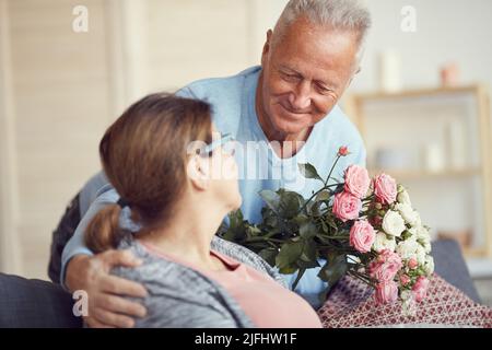 Heureux beau gris-cheveux homme se pliant à la femme et lui donnant un beau bouquet le jour de Valentines Banque D'Images