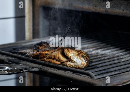 Processus de cuisson du poisson de la mer entière sur un barbecue au charbon chaud. Dorado grillé Banque D'Images