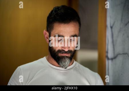 Jeune homme devant un miroir pour se laver le visage, raser la barbe ou brosser les dents. Photo de haute qualité Banque D'Images