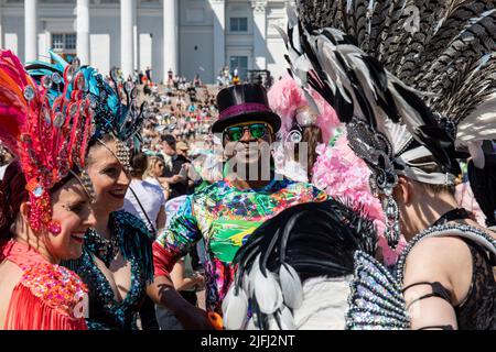 Homme souriant portant des lunettes de soleil et un chapeau haut ou un chapeau haut entouré par les interprètes du défilé du carnaval de Samba d'Helsinki sur la place du Sénat, Helsinki, Finlande. Banque D'Images