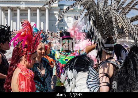 Danse masculine souriante de samba portant un chapeau et des lunettes de soleil entouré par les mêmes danseuses en costumes sur la place du Sénat avant le carnaval de samba d'Helsinki Banque D'Images