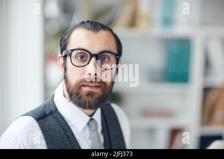 Portrait d'un jeune entrepreneur barbu intelligent et effrayé en lunettes travaillant au bureau Banque D'Images