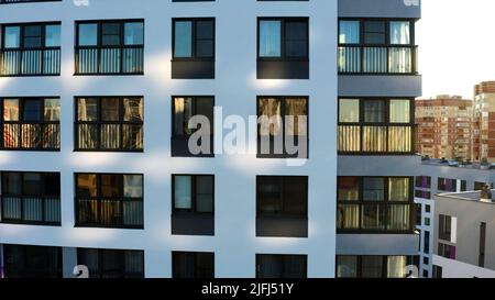 Fenêtres sombres du bâtiment blanc de plusieurs étages. Films. Vue aérienne d'un appartement résidentiel gratte-ciel par une journée ensoleillée d'été. Banque D'Images