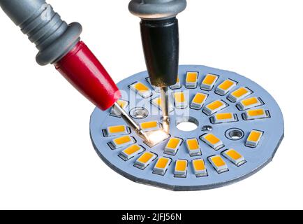 Sondes de test électriques pointues sur diode LED allumée isolée sur fond blanc. Diodes électroluminescentes électroniques jaunes sur la carte en aluminium de refroidissement. Banque D'Images