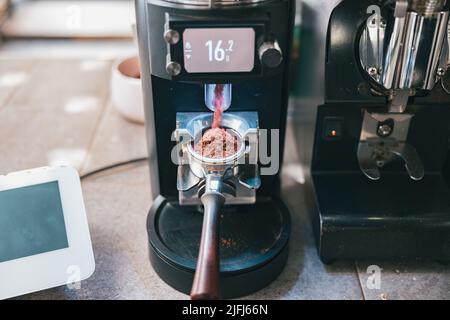 Processus de broyage des grains de café versant dans un porte-filtre à l'aide d'une machine à café Banque D'Images