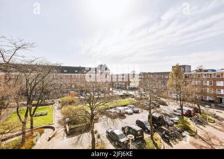 Panorama de maisons en briques avec un grand parking avec des voitures et des vélos, avec une pelouse, des arbres et des lanternes par temps ensoleillé Banque D'Images