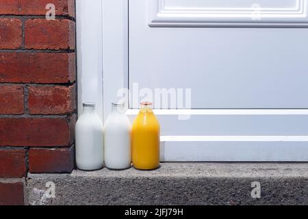 Pintes de lait et une pinte de jus d'orange frais à la porte livrée par un milkman Banque D'Images