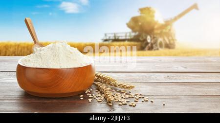 Placer la farine de blé sur une table en bois dans le champ avec la moissonneuse-batteuse Banque D'Images