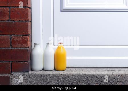 Pintes de lait et une pinte de jus d'orange frais à la porte livrée par un milkman Banque D'Images