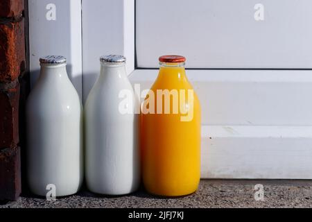 Pintes de lait et une pinte de jus d'orange frais à la porte livrée par un milkman Banque D'Images