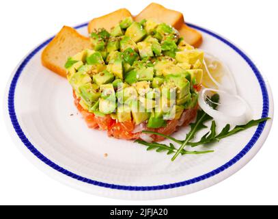 Tartare de saumon à l'avocat servi avec de l'arugula, de l'oignon, du citron et des toasts Banque D'Images