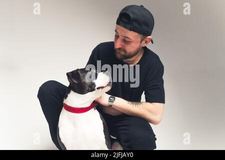 chien d'amstaff en laisse rouge regardant son studio de propriétaire mâle tourné fond gris isolé . Photo de haute qualité Banque D'Images