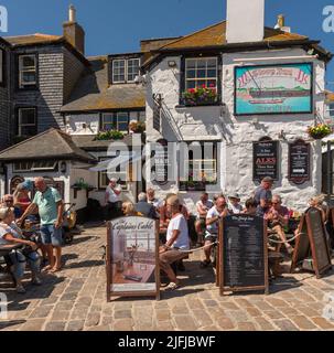 St Ives, Cornouailles, Angleterre, Royaume-Uni. Pub clients manger et boire dehors au soleil dans une célèbre vieille maison publique sur le port à St Ives, Cornwall, Banque D'Images