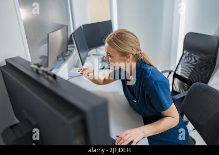 L'infirmière en service fait une annonce dans le microphone du bureau de réception de la clinique moderne Banque D'Images