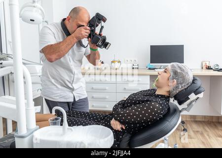 Dentiste photographiant les dents du patient à des fins de dossier médical avant et après la chirurgie dans le cabinet du dentiste Banque D'Images
