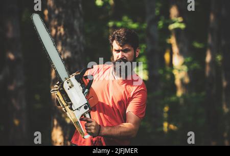 Beau jeune homme avec hache près de la forêt. Déforestation. Bûcheron dans les bois avec hache à tronçonneuse. Thème de l'agriculture et de la foresterie Banque D'Images