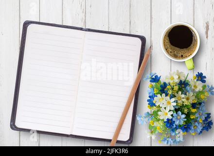 Vue de dessus de bureau table de bureau avec cahier à spirale ouvert, crayon, tasse de café et fleur sur fond de table en bois blanc. Le monde des affaires et de l'éducation concep Banque D'Images