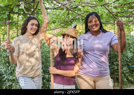 Portrait de trois femmes tenant des outils de jardin dans un jardin urbain. Banque D'Images
