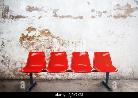 Chaise rouge dans une pièce vide contre un mur extérieur de briques de bâtiments anciens, le concept commercial et marketing, l'espace de copie pour le texte ou le média con Banque D'Images