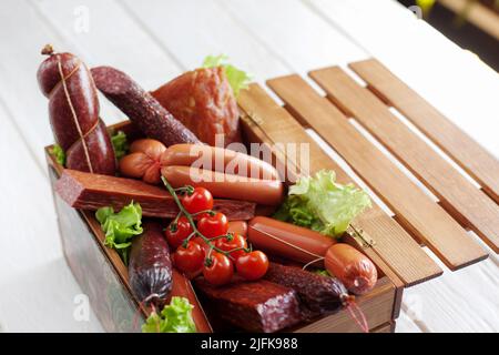 Assortiment de saucisses dans une boîte en bois sur fond blanc Banque D'Images