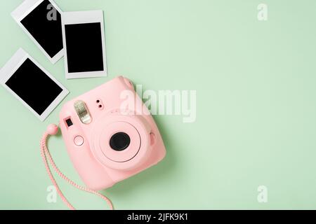 La caméra instantanée rose avec des films instantanés vierges sur fond vert. Banque D'Images