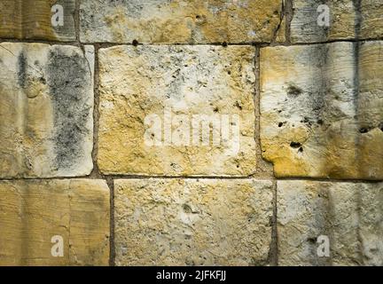 Grand mur en pierre d'un vieux bâtiment, avec beaucoup de texture et de tons chauds, à utiliser comme pochoir ou comme fond. Banque D'Images