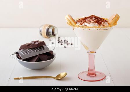 Tiramisu fait maison rapide pour une visite inattendue, dessert sucré sans cuisson de type cheesecake avec des ingrédients placés sur une table en bois blanc. Banque D'Images