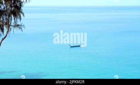 Seul petit bateau sur une surface de mer bleue propre. Bateau thaïlandais traditionnel en bois naviguant dans une mer calme et ouverte en été. Paysage tropical lumineux, exotique Banque D'Images