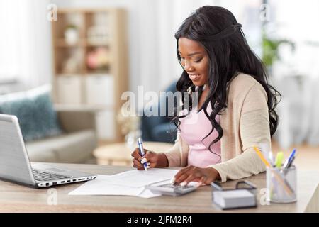 femme avec calculatrice et papiers travaillant à la maison Banque D'Images
