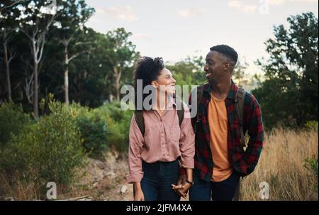 Un jeune couple multiethnique souriant se tenant ensemble pendant une randonnée sur les sentiers Banque D'Images