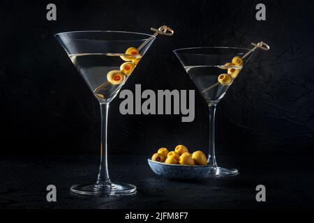 Martini, deux verres aux olives épicées, sur fond noir. Cocktail alcoolisé Banque D'Images