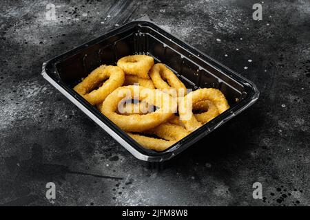 Cercueil cru congelé ou rondelles d'oignon panées, sur fond de table en pierre noire sombre Banque D'Images