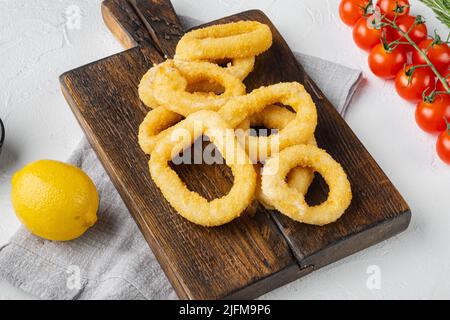 Rondelles de calmar frites panées, sur plateau de service, sur fond de table en pierre blanche Banque D'Images