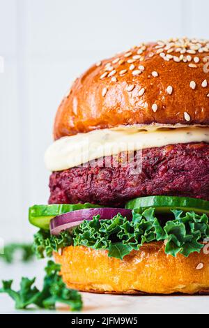 Hamburger végétarien aux betteraves avec chou vert, oignon et concombre, gros plan. Aliments de restauration rapide alternatifs. Cuisine pourpre. Banque D'Images