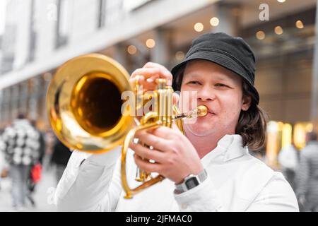 Jeune caucasien en chemise blanche et chapeau jouant du jazz sur la trompette à l'extérieur Banque D'Images