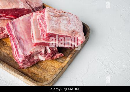 Côtes de bœuf marbré Angus noir brut, sur fond de pierre blanche, avec espace pour le texte Banque D'Images