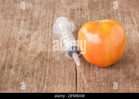 Tomate fraîche et seringue sur une table en bois Banque D'Images